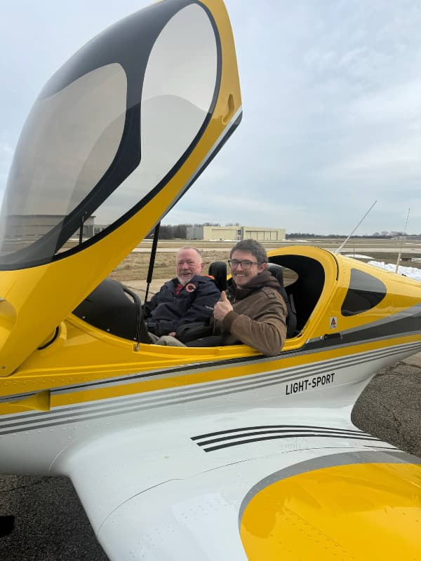 A student and instructor in the cockpit of a yellow Bristell with the canopy open