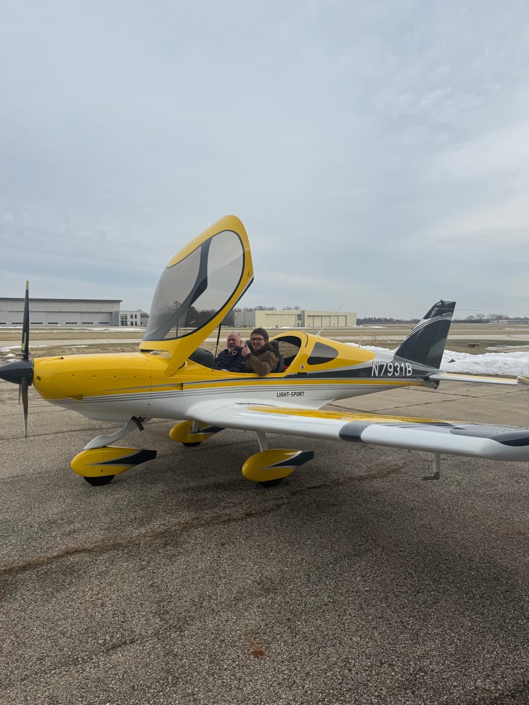 An instructor and student seated together in the cockpit of a yellow Bristell