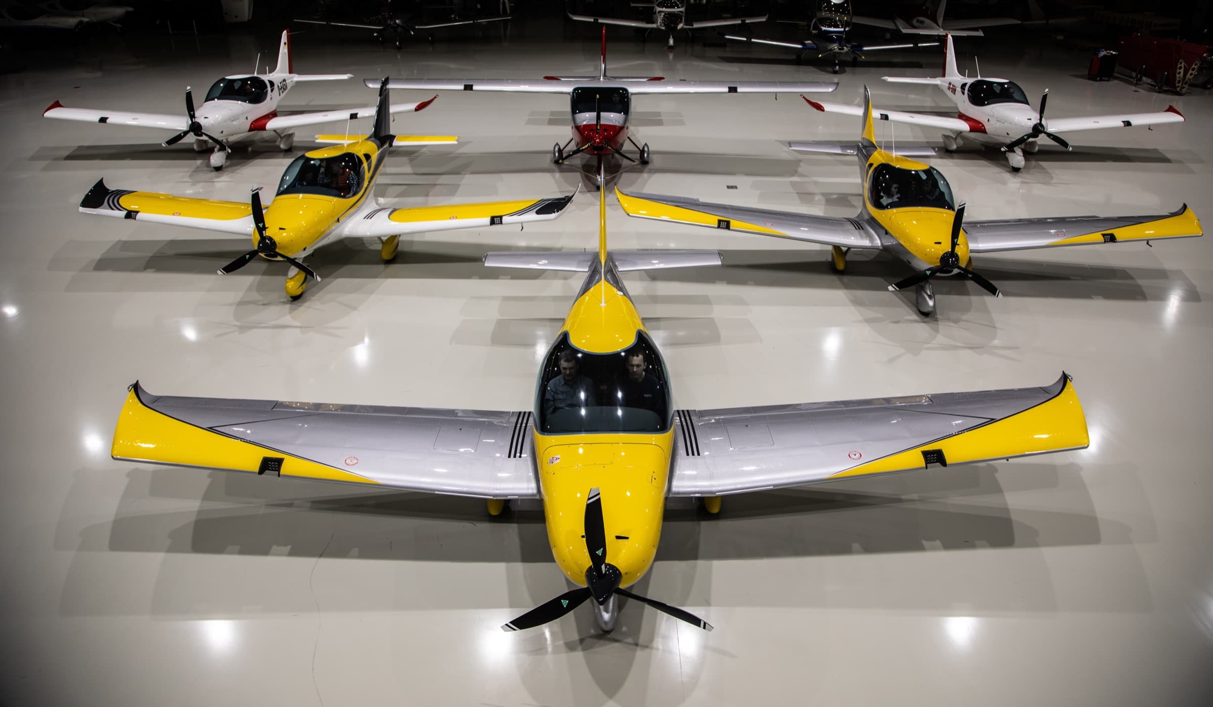 Yellow and silver Bristell aircraft lined up inside a bright hangar